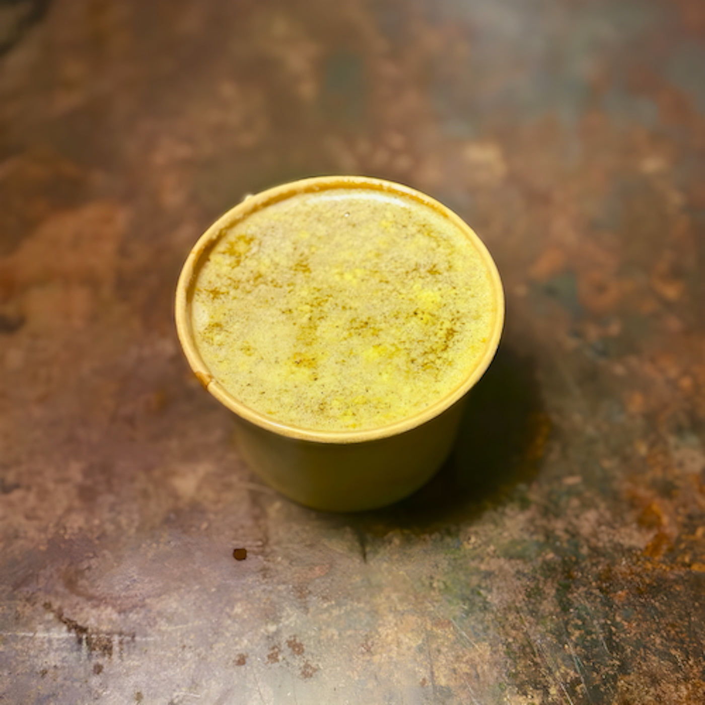 Yellow container with a lid on a rusty metal surface