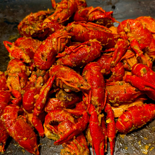 Close-up of a Cajun seafood boil featuring lobster tail, shrimp, crawfish, crab, corn, and potatoes, coated in buttery seasoning for a rich, flavorful seafood boil presentation.