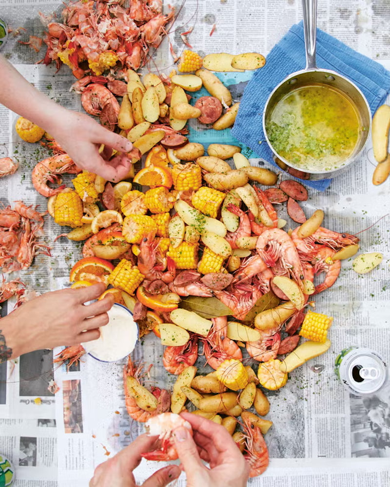 A complete Cajun seafood boil featuring shrimp, snow crab, crawfish, corn on the cob, baby potatoes, cornbread, garlic butter, and fresh lemon served on butcher paper by Boil Baby Boil in Los Angeles.