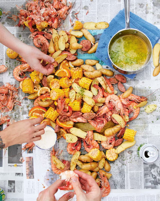 A complete Cajun seafood boil featuring shrimp, snow crab, crawfish, corn on the cob, baby potatoes, cornbread, garlic butter, and fresh lemon served on butcher paper by Boil Baby Boil in Los Angeles.