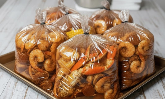 Spicy Cajun seafood boil in clear plastic bags filled with crab legs, corn, and seasoned butter sauce, ready to serve.