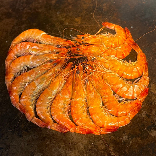 Fresh cooked prawns arranged in a circle on a hot griddle, commonly used in Cajun seafood boils in Los Angeles.