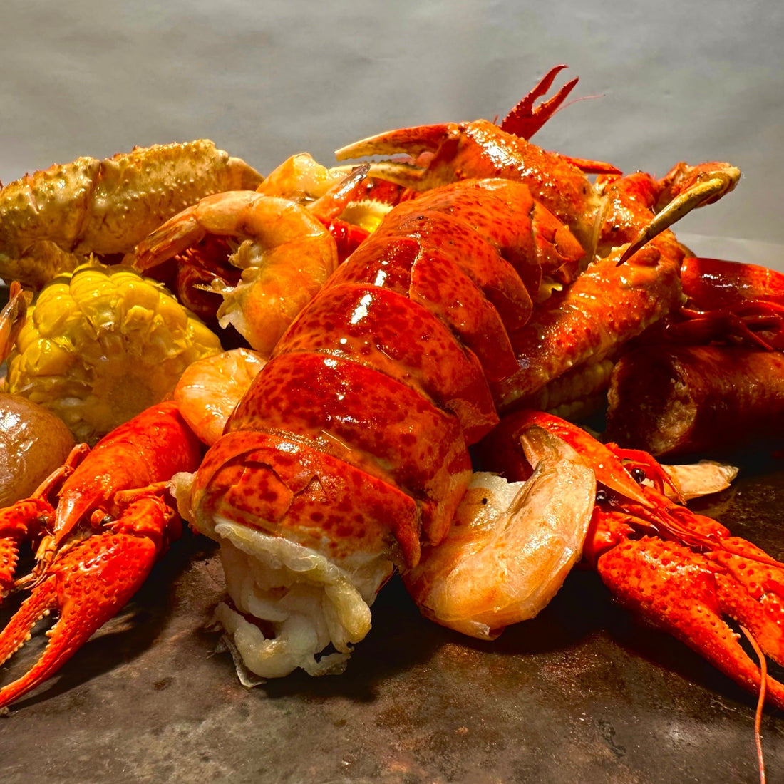 Lobster, shrimp, crawfish, crab, corn, and potatoes in a buttery Cajun seafood boil, showcasing fresh shellfish and rich spices for an authentic seafood boil feast.