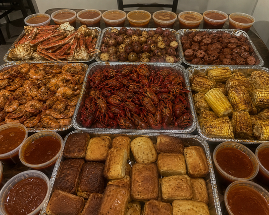Massive Louisiana-style seafood boil feast featuring 10 pounds of shrimp, 2 pounds of prawns, 6 pounds of snow crab legs, 12 pounds of crawfish, 4 pounds of andouille sausage, 10 pounds of seasoned baby potatoes, sweet corn on the cob, homemade cornbread, and Cajun butter dipping sauces. Authentic iPhone-style food photography showcasing a family-sized seafood boil catering spread on a dining table, perfect for parties, weddings, corporate events, birthdays, and seafood catering in Los