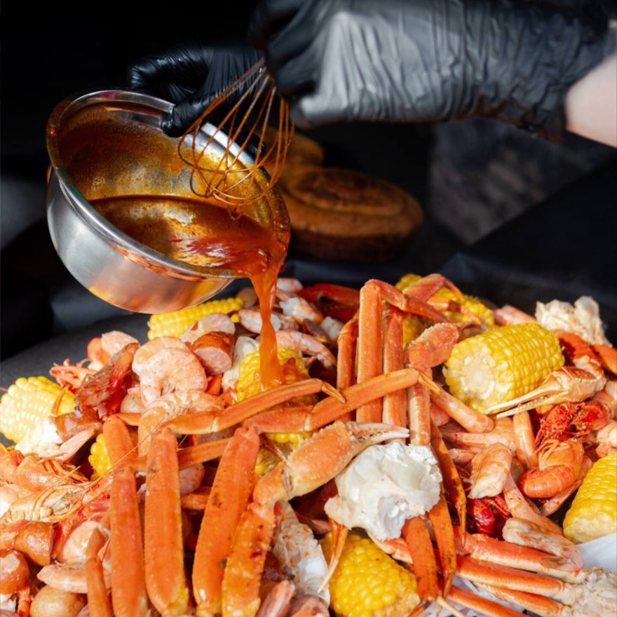 Cajun seafood boil platter with crawfish, shrimp, and corn drizzled with sauce in Los Angeles