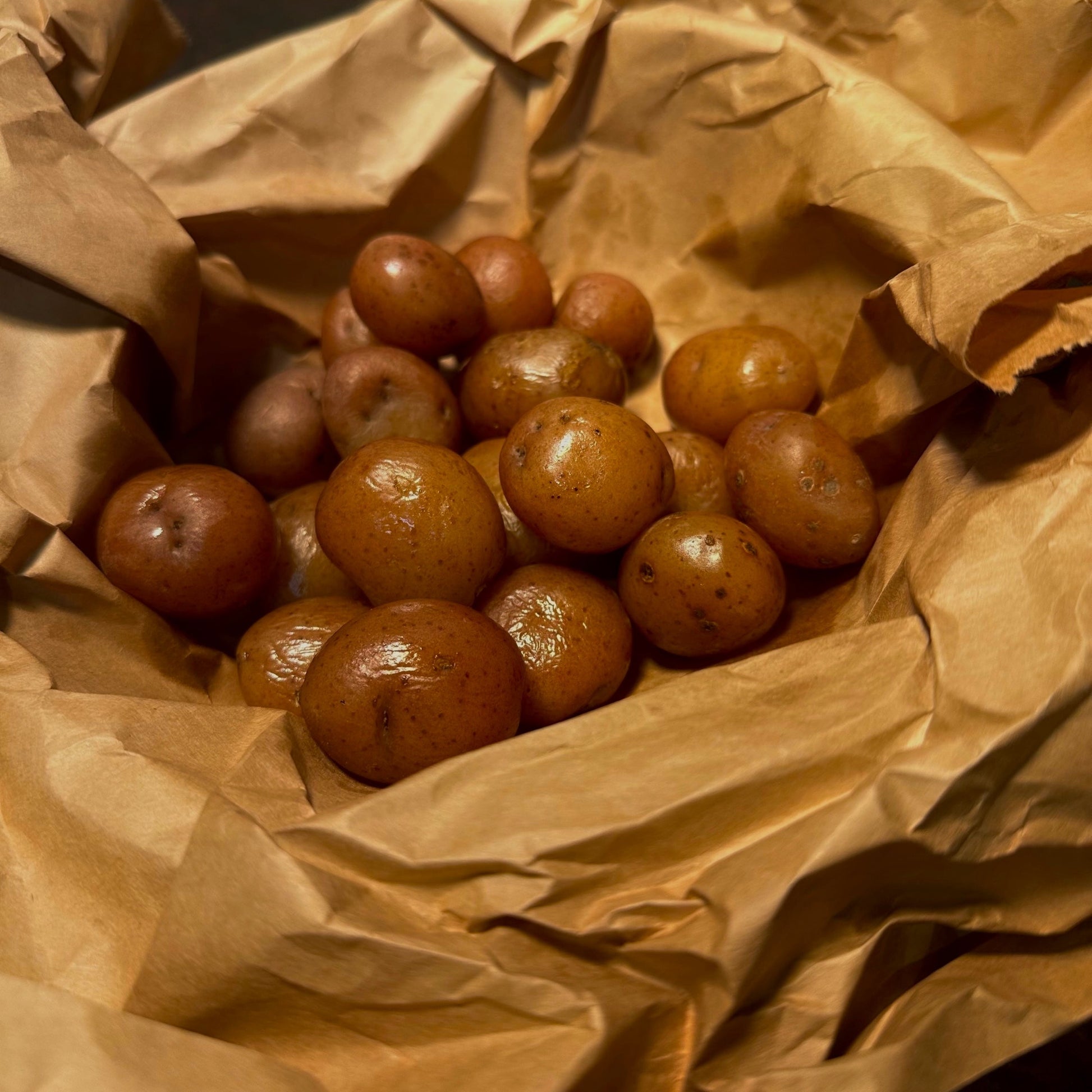 Steamed baby red potatoes glistening with butter, served in brown butcher paper for a rustic seafood boil presentation.
