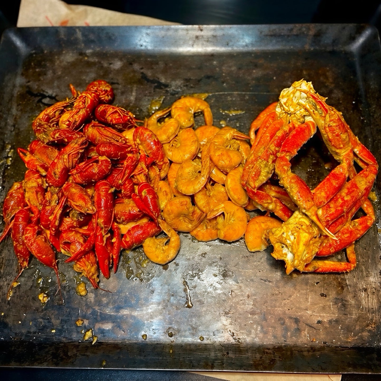 Assorted cooked crawfish and shrimp on a metal tray. Seafood boils in Los Angeles