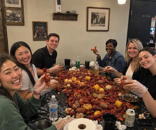 Friends enjoying a Cajun crawfish seafood boil catering feast with crawfish, corn and potatoes in Los Angeles.