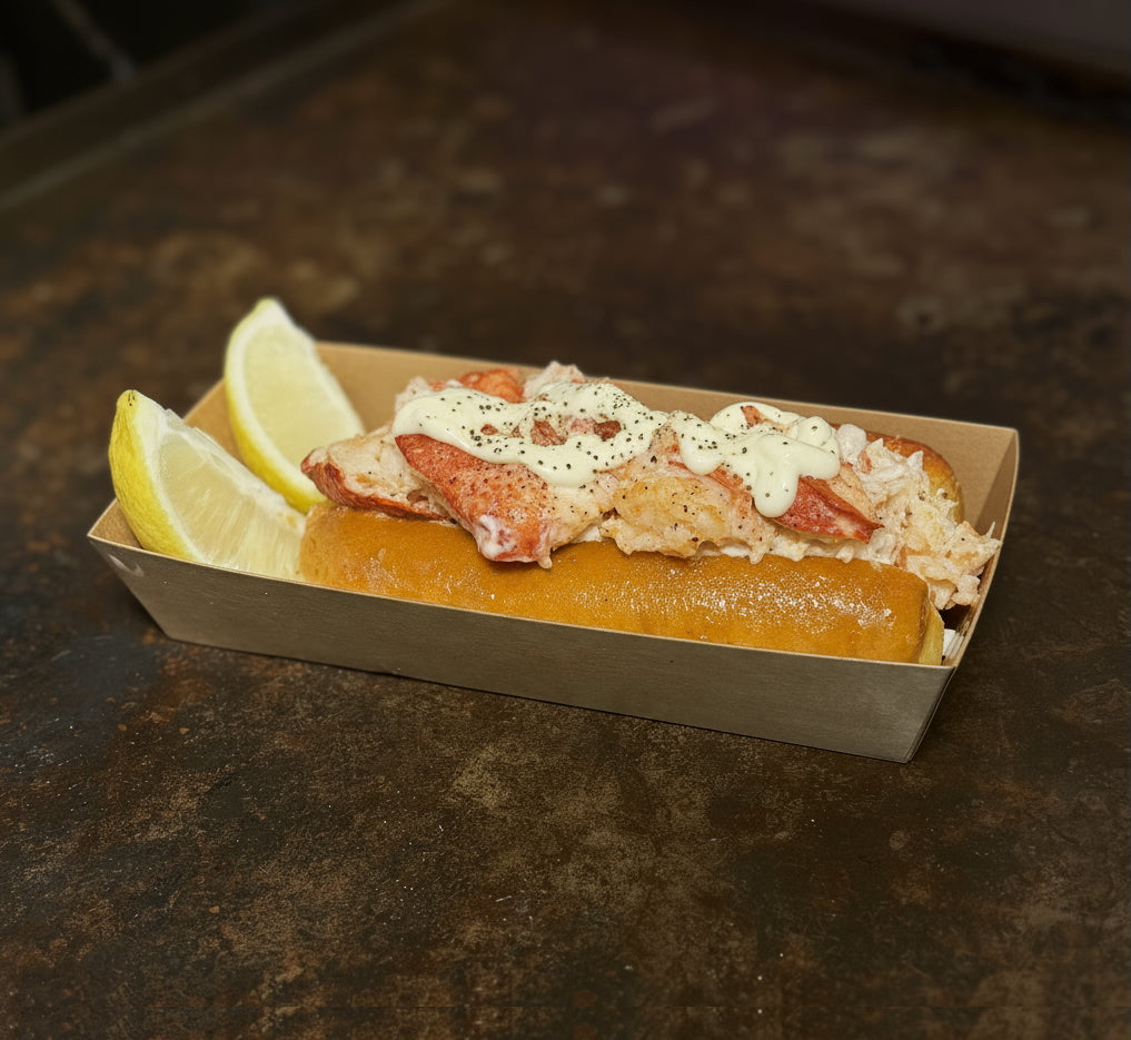Lobster roll with lemon wedges served in cardboard container at Cajun seafood boil restaurant in Los Angeles
