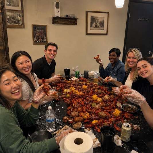 Office catering in Los Angeles with coworkers enjoying a seafood boil featuring lobster tails, shrimp, corn and potatoes, served family-style with gloves for a fun group lunch.