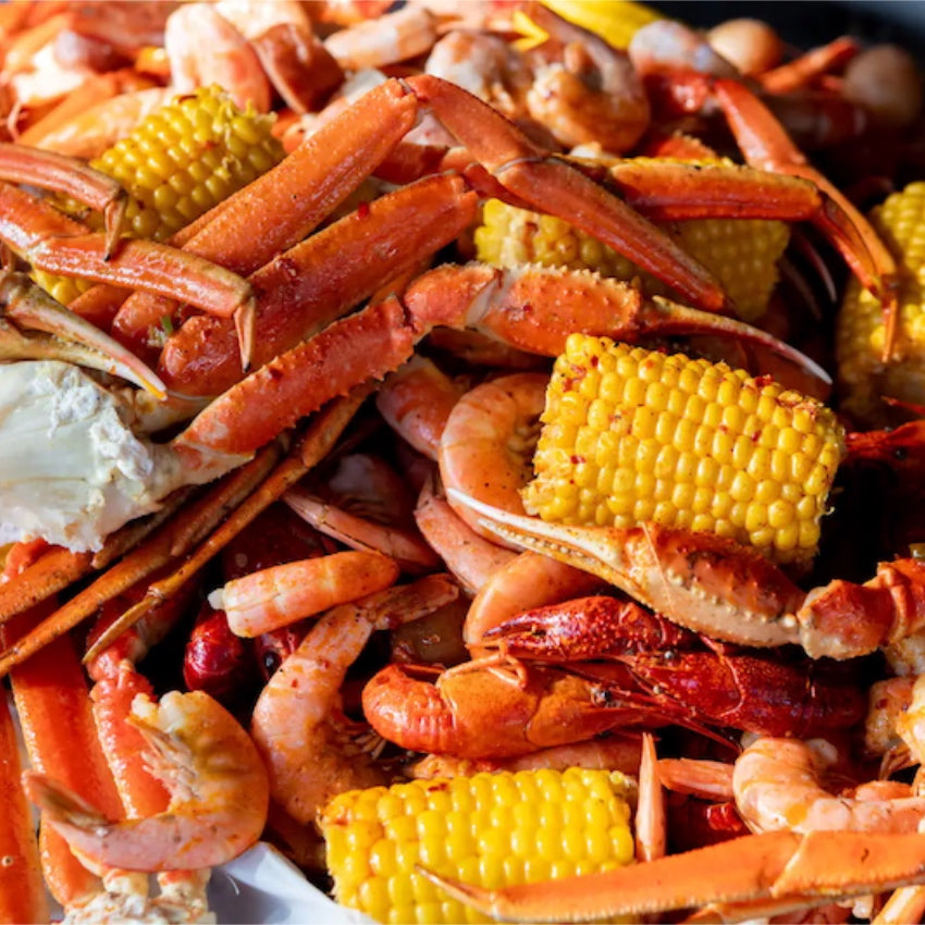 Assorted seafood including crab legs, shrimp, and corn on the cob.
