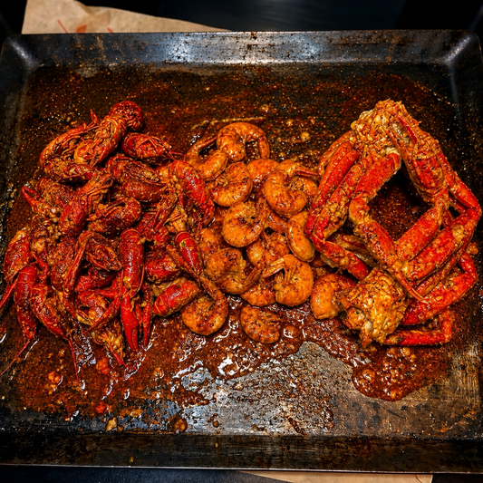 Boil Baby Boil seafood tray loaded with spicy crawfish, jumbo shrimp, and crab legs coated in rich Cajun seasoning sauce